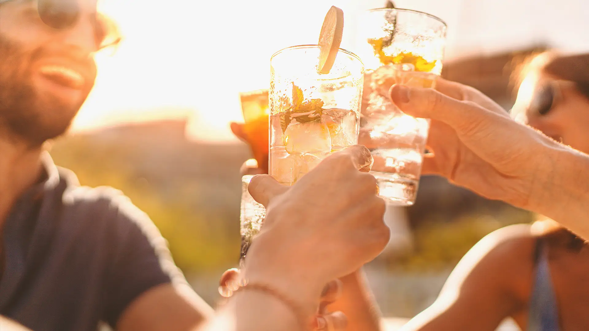 Sunny outdoor cheers with cocktails and friends at a casual celebration Group of friends toasting with citrus cocktails in the sun during a relaxed outdoor gathering